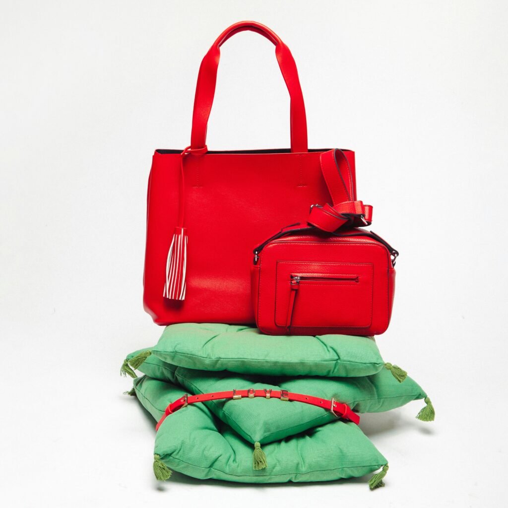 Fashionable red handbags elegantly displayed on green pillows against a white background.